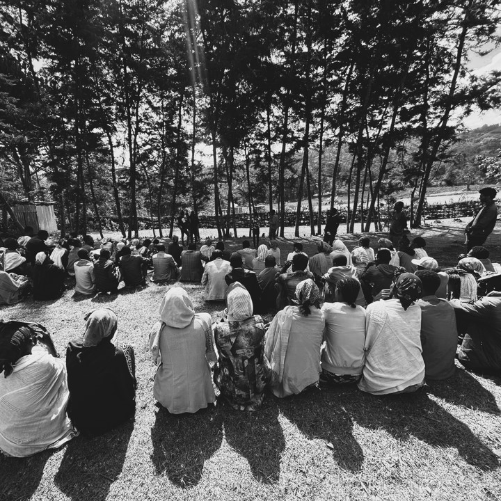A group of Ethiopian farmers sitting outside, attending a training session on financial literacy